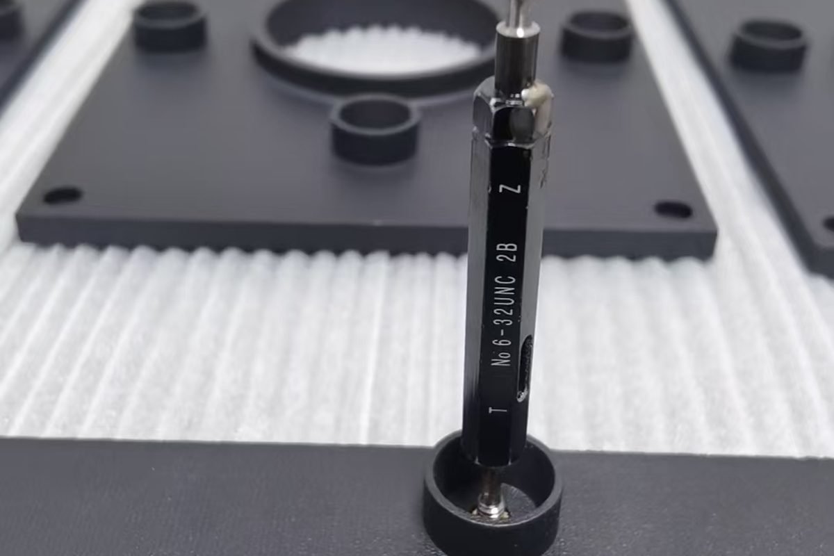 A thread plug gauge checking a tapped hole in a printed component