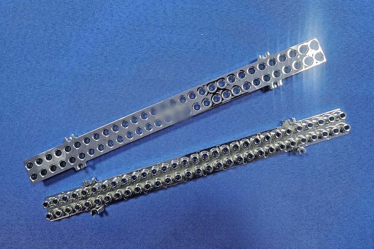 Two plated injection-molded components on a blue inspection background